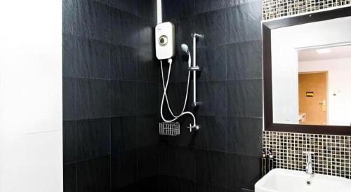 a black tiled bathroom with a shower and a mirror at The Circle Hotel in Buriram