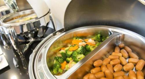 a pot of food with broccoli and beans on a stove at The Circle Hotel in Buriram