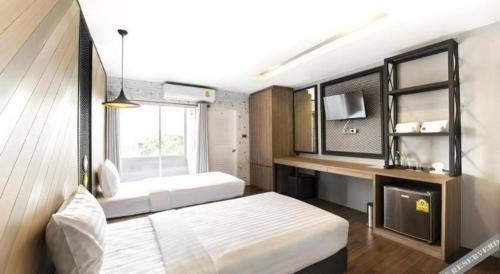 a bedroom with a bed and a desk and a window at The Circle Hotel in Buriram