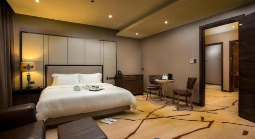 a bedroom with a large bed and a desk and a table at Lotus Blu Hotel in Legazpi