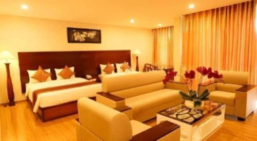 a living room with two beds and a couch at New Palace Bac Lieu Hotel in Bạc Liêu