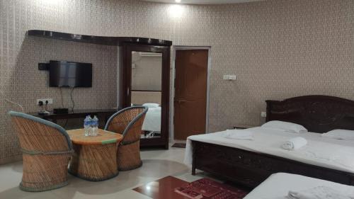 a hotel room with a bed and a table and chairs at Gopala Grand in Jabalpur