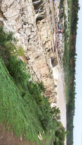 a road next to a rocky hill with a grassy field at Gopala Grand in Jabalpur