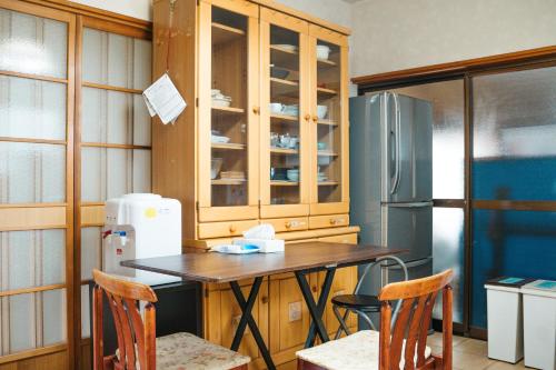 a kitchen with a table and chairs and a refrigerator at 木の家ゲストハウス松山本館 in Hoshioka