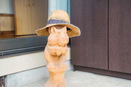 a statue of a cat wearing a straw hat at 木の家ゲストハウス松山本館 in Hoshioka
