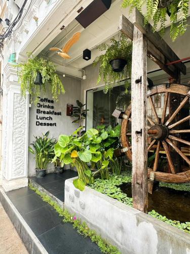プーケットタウンにあるBeanstay hostelの大きな木製の車輪と植物のある店先