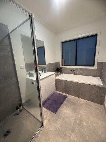a bathroom with a shower and a tub and a sink at Peaceful Private Room in Wyndham Vale in Wyndham Vale