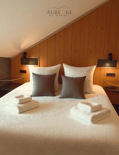 a large white bed with three towels on it at Logis Auberge du Barrez in Mur-de-Barrez