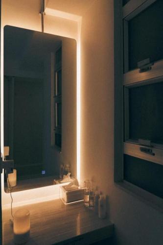 a bathroom with a mirror and a sink with a light at SLEEEP HKG Causeway Bay in Hong Kong
