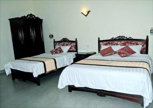 a bedroom with two beds with white and red pillows at Hai Au Hotel in Hai Phong