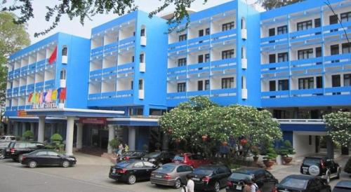 a blue building with cars parked in a parking lot at Hai Au Hotel in Hai Phong