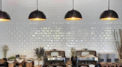 a kitchen with three pendant lights and a white wall at XOTEL in Khon Kaen