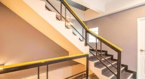 a metal staircase with yellow railing in a house at OYO 726 Sookjai Cafe and Hostel in Chiang Mai