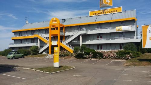 a building with a yellow sign in a parking lot at Première Classe Troyes Sud - Buchères in Troyes
