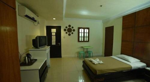 a bedroom with a bed and a television and a table at Marcian Business Hotel in Zamboanga