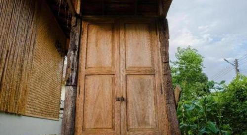 a wooden door on the side of a building at Nornnadubua in Uthai Thani