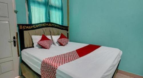 a bedroom with a bed with red and white pillows at Hotel O Rania Kost Simpang Rimbo in Jambi