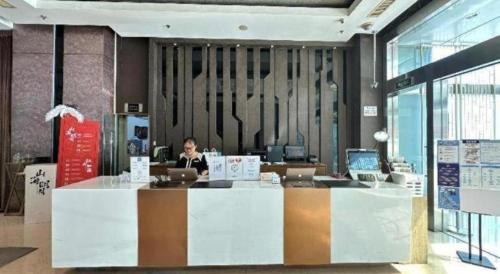 a woman sitting at a desk with a laptop at Kingtown Hotel Hongqiao Shanghai in Shanghai