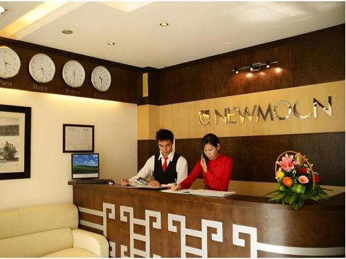 a man and woman sitting at a reception desk at New Moon Hotel in Hanoi
