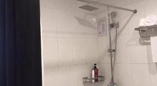 a shower in a bathroom with a white tiled wall at New Moon Hotel in Hanoi
