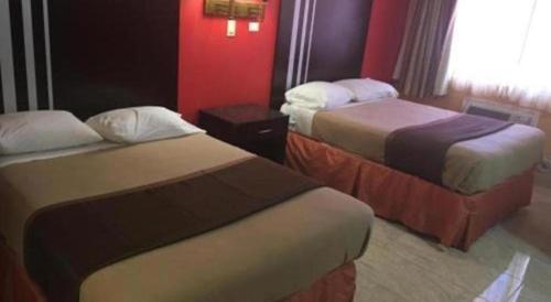 two beds in a hotel room with red walls at Travelodge by Wyndham Bay Shore Long Island in Bay Shore