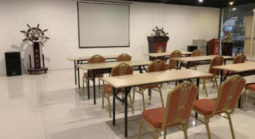 a classroom with tables and chairs and a white wall at GreenTree Inn Taizhou New District Hospital of Renmin Hospital Mingliu Express Hotel in Jiuligou