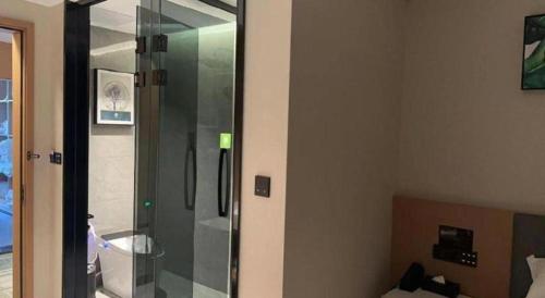 a bathroom with a shower with a glass door at GreenTree Inn Taizhou New District Hospital of Renmin Hospital Mingliu Express Hotel in Jiuligou