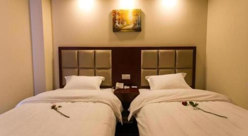 two beds in a hotel room with white sheets at GreenTree Inn Suzhou Guanqian Street Leqiao Metro Station in Suzhou