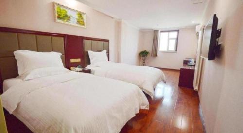 a hotel room with two beds and a television at GreenTree Alliance Zhejiang Zhoushan Putuoshan Zhujiajian Scenic Spot Hotel in Zhoushan