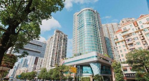a tall building in a city with tall buildings at Grand Soluxe Zhongyou Hotel Shenzhen in Shenzhen