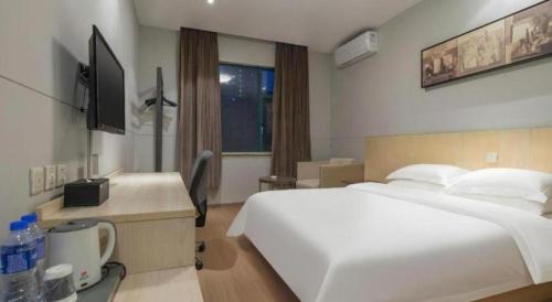 a bedroom with a large white bed and a television at Jinjiang Inn Wenzhou Shuangyu The Terminal in Wenzhou