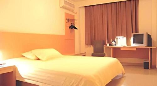a bedroom with a bed and a desk and a television at Jinjiang Inn Wenzhou Shuangyu The Terminal in Wenzhou