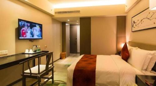 a bedroom with a bed and a desk and a tv at Chambery Hotel in Zhuhai