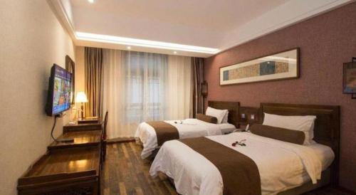 a hotel room with two beds and a flat screen tv at James Joyce Coffetel Xian Dayanta Metro Station Branch in Xi'an