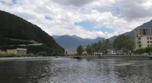 a large body of water with buildings and mountains at GreenTree Inn Tibet Nyingchi City Biji Shenshan in Nyingchi