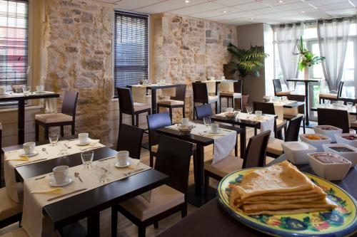 a restaurant with tables and chairs and a plate of bread at L'herbier d'Orange in Orange