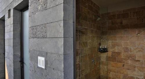 a bathroom with a shower with a stone wall at Pu Luong Hostel in Ải Hạ