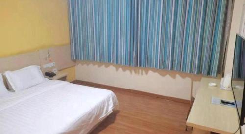 a bedroom with a bed and a desk and a window at 7 Days Inn Yining Xintiandi in Kipekyüzi