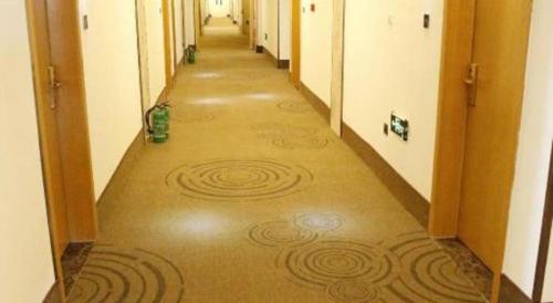 an empty hallway with a carpeted floor in a building at GreenTree Inn Ordos Kangbashi District Ulan Mulun Street Branch in Ordos