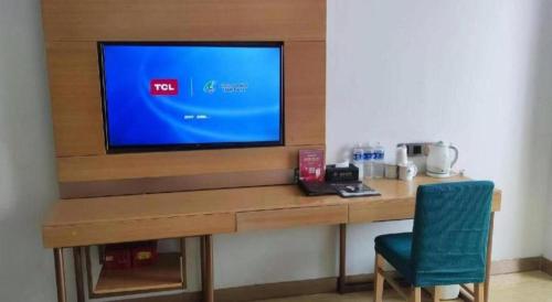 a television sitting on top of a desk with a chair at GreenTree Inn Ordos Kangbashi District Ulan Mulun Street Branch in Ordos