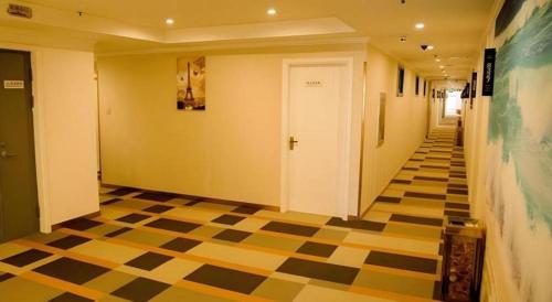 a hallway with a checkered floor and a white door at Shell Shanghai Songjiang District Xinqiao Town Xinqiao Hotel in Chunshen