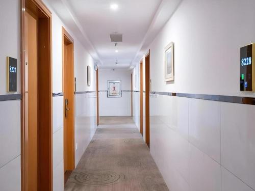 a hallway with white walls and a long hallway with doors at GreenTree Inn Wuxi Xinwu District Meicun Town Taibo Avenue in Wuxi