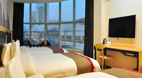 a hotel room with two beds and a desk with a monitor at Thank Hotel Jiangxi Jiujiang Lianxi District Railway Station Square in Jiujiang