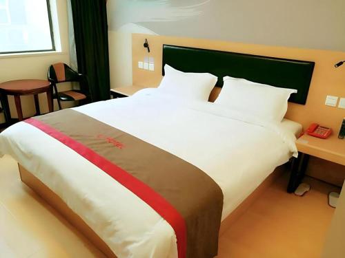 a bedroom with a large white bed with a green headboard at Thank Hotel Jiangxi Jiujiang Lianxi District Railway Station Square in Jiujiang