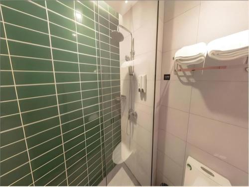 a bathroom with green and white tiled walls and a shower at GreenTree Inn Yichun Mingyueshan Airport in Yichun