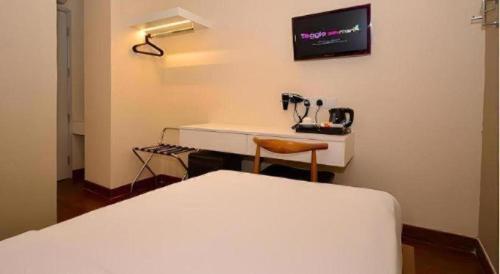 a bedroom with a bed and a desk with a television at The Keong Saik Hotel in Singapore