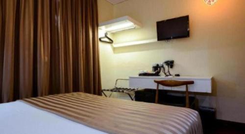 a hotel room with a bed and a desk and a television at The Keong Saik Hotel in Singapore