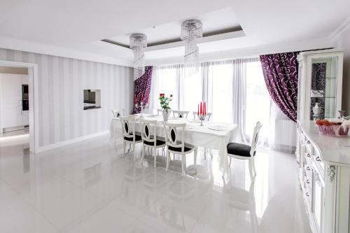 a white dining room with a white table and chairs at Pensiunea Primaverii in Satu Mare