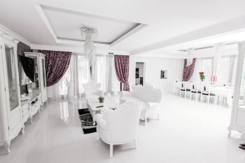 a white living room with white furniture and windows at Pensiunea Primaverii in Satu Mare