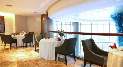 a restaurant with white tables and chairs and a large window at Wuhan Gleetour Hotel in Wuhan